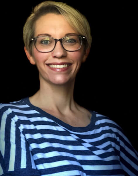 A woman with glasses and blonde hair wearing a striped shirt.