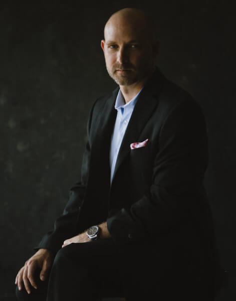 A man in a suit and tie sitting down.