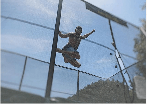 A man jumping in the air on top of a trampoline.